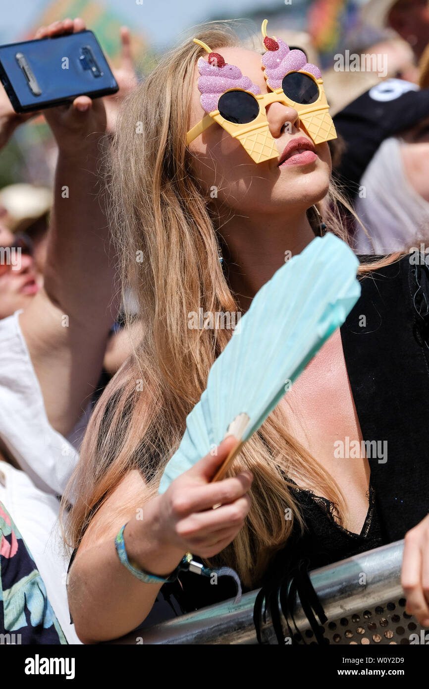 Pilton, Somerset, Regno Unito. Il 28 giugno 2019. Una donna con gelato di occhiali da sole e una ventola in mezzo alla folla Glastonbury Festival 2019 venerdì 28 giugno 2019 presso l'azienda agricola degna, Pilton. Cercando di mantenere fresco come Sheryl Crow gioca . Foto di credito: Julie Edwards/Alamy Live News Foto Stock