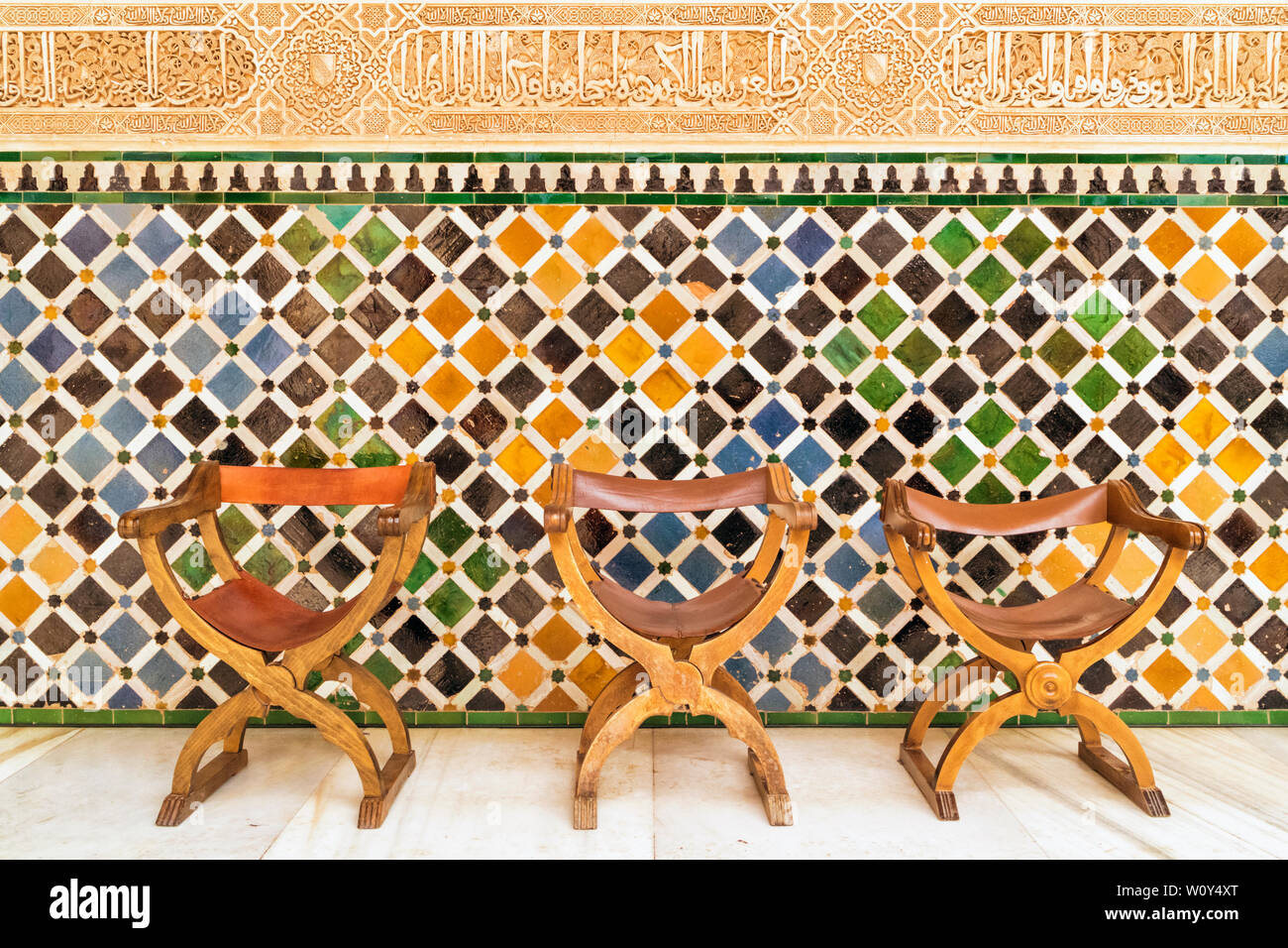 Di stile Spagnolo sedie contro una parete a mosaico nel cortile dei Mirti, l'Alhambra di Granada, provincia di Granada, Andalusia, Spagna meridionale. La A Foto Stock