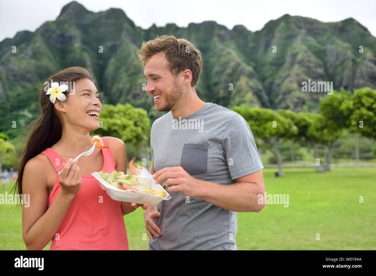 Hawaii viaggi alimentari paio mangiare aglio gamberetti su Oahu North Shore. Popolari di gamberi hawaiano cibo carrello pasto su strada il concetto di viaggio. Foto Stock
