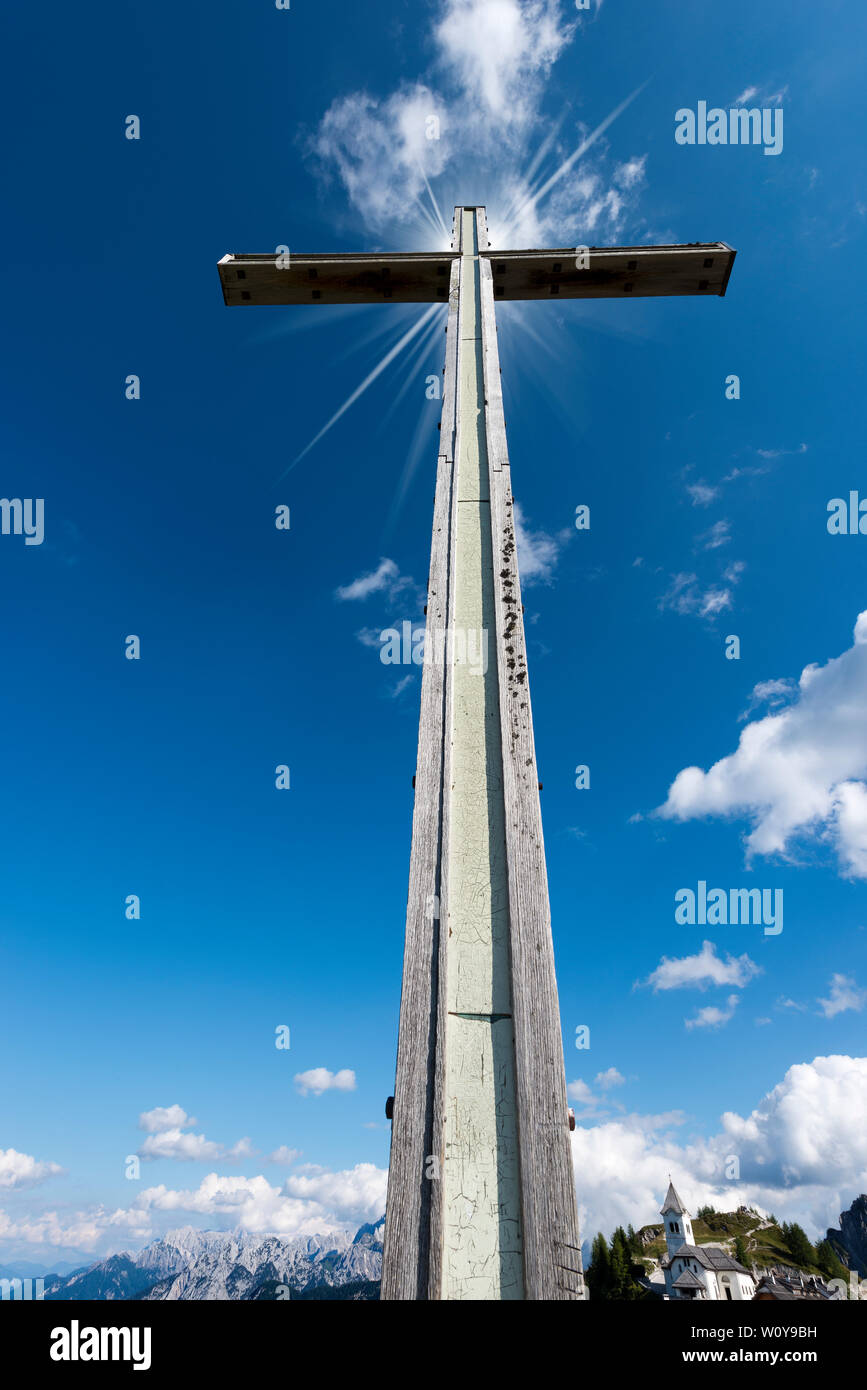 Alta in legno croce sul cielo blu con nuvole. Antico borgo di Monte Santo di Lussari, sulle Alpi Giulie. Udine Friuli Venezia Giulia, Italia, Europa Foto Stock