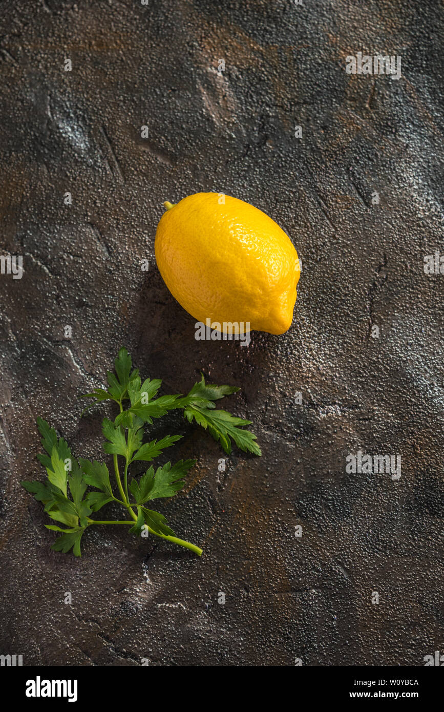 I limoni con prezzemolo su sfondo scuro Foto Stock