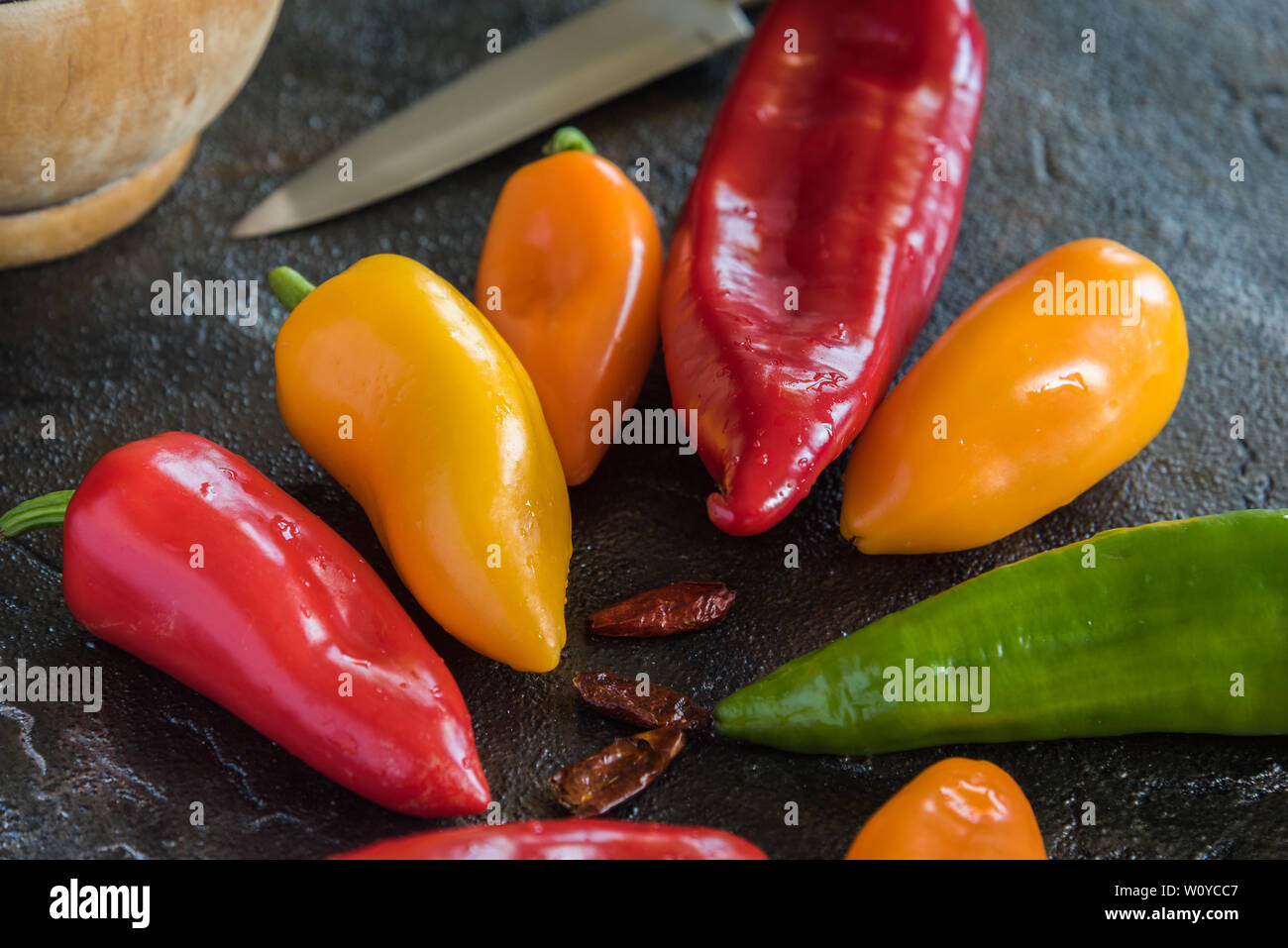 Peperoni di vari colori al buio su un sfondo di pietra Foto Stock