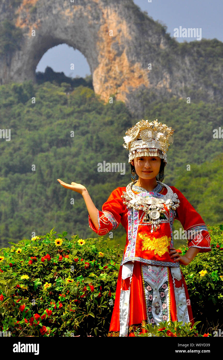 Una ragazza cinese pone in locali etnici abito di fronte luna hill, Yangshuo, Guilin Cina Foto Stock