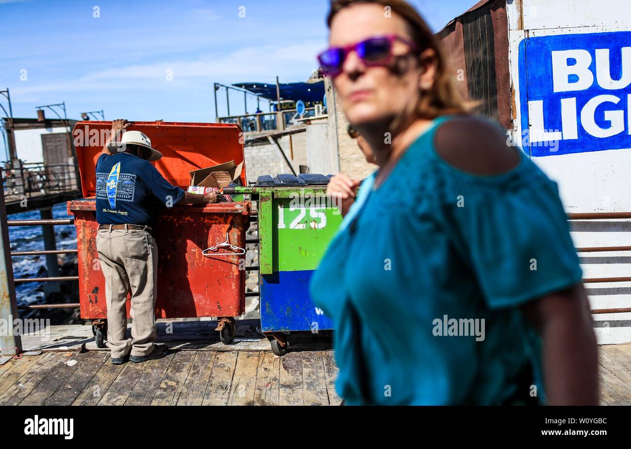 Puerto Peñasco, Sonora, 20 ottobre 2017.- due donne americane turisti passeggiata del porto turistico di Puerto Peñasco mentre un Maggio uomo adulto di estrema povertà cerca di cibo all'interno di contenuti del Cestino. Dos mujeres turistas norteamericanas pasean por el muelle turístico de Puerto Peñasco mientras onu hombre adulto mayo de pobreza extrema busca comida dentro de los contenidos de basura. (Foto: Luis Gutierrez /NortePhoto.com) Foto Stock