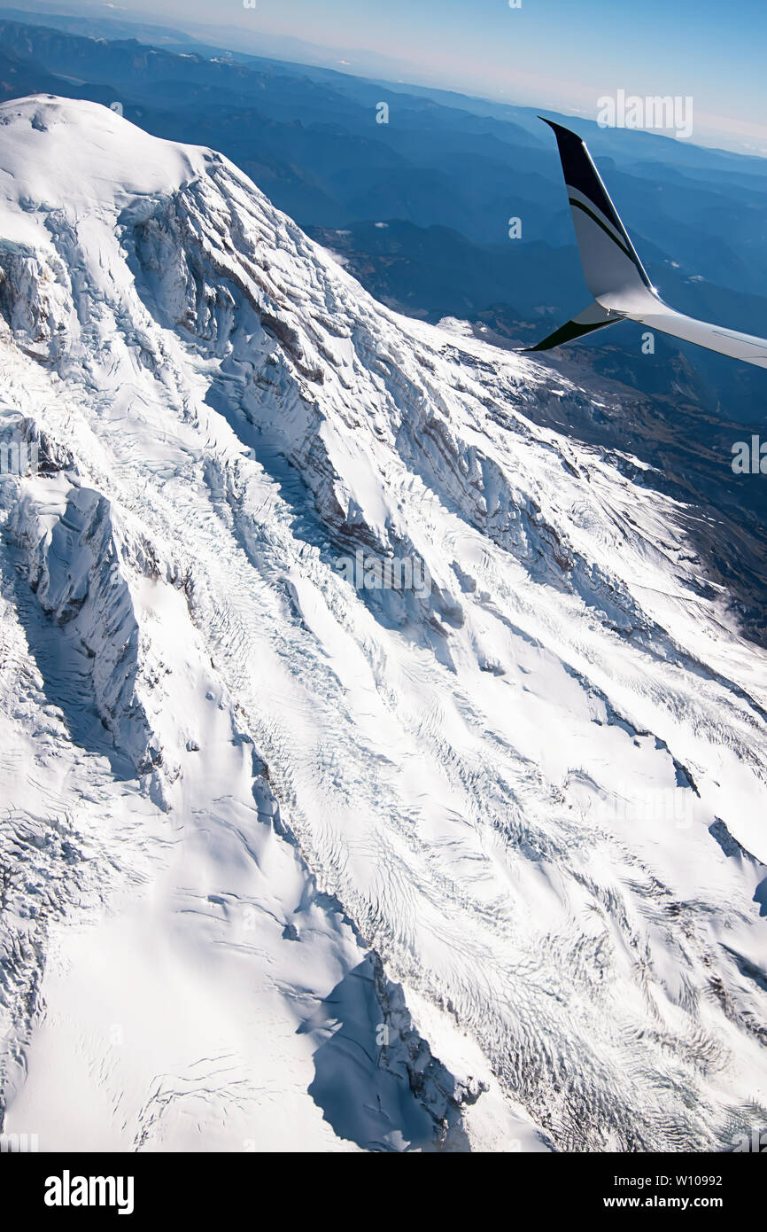 Il Monte Rainier, Washington, Stati Uniti d'America vista aerea di snow-capped mountain visto dalla finestra aereo con il piano ala e Blue Horizon in vista Foto Stock