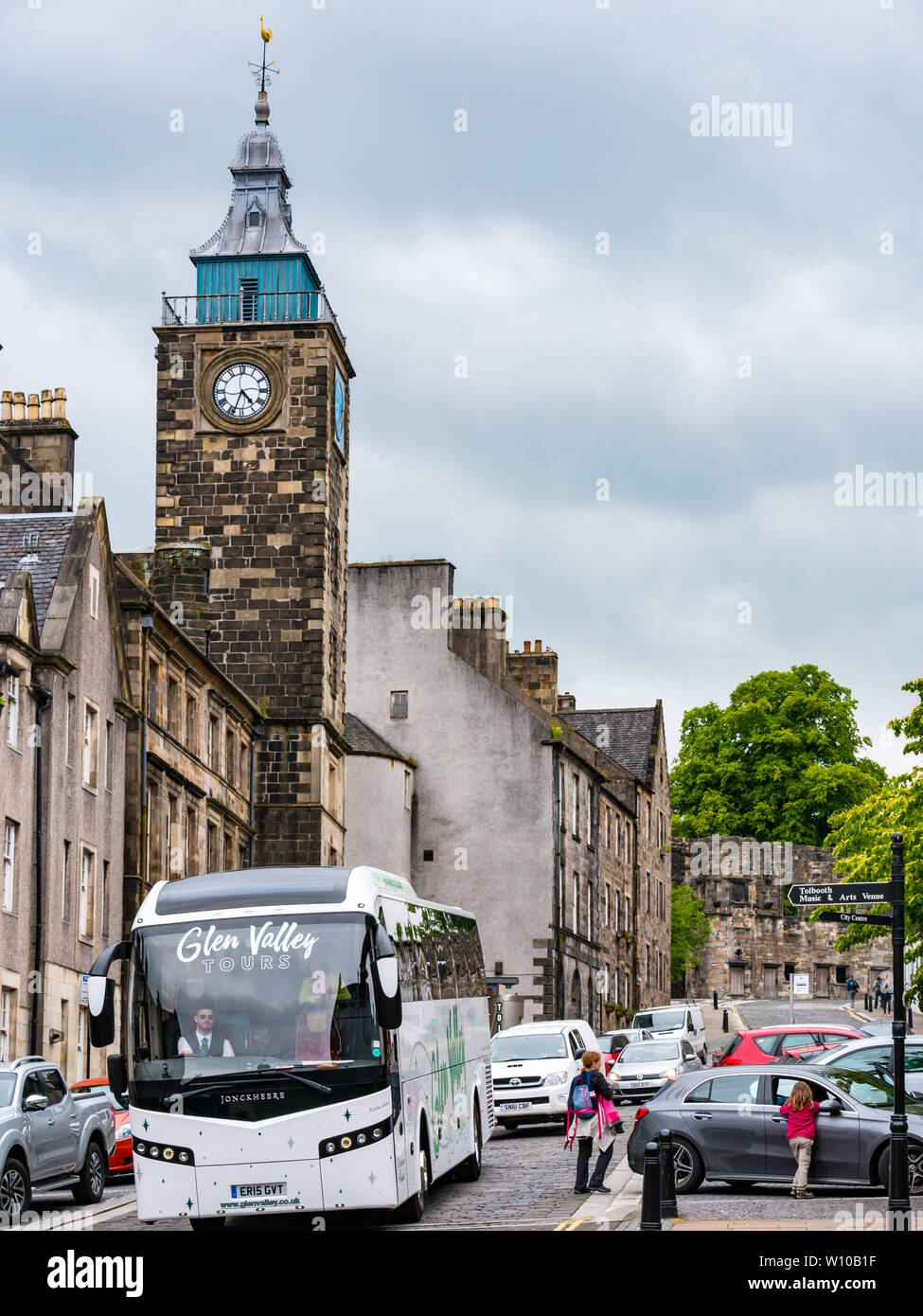 Pullman turistico la guida sulle strette vecchia strada di ciottoli con Tolbooth torre e orologio, Broad Street, Stirling Old Town, Scotland, Regno Unito Foto Stock
