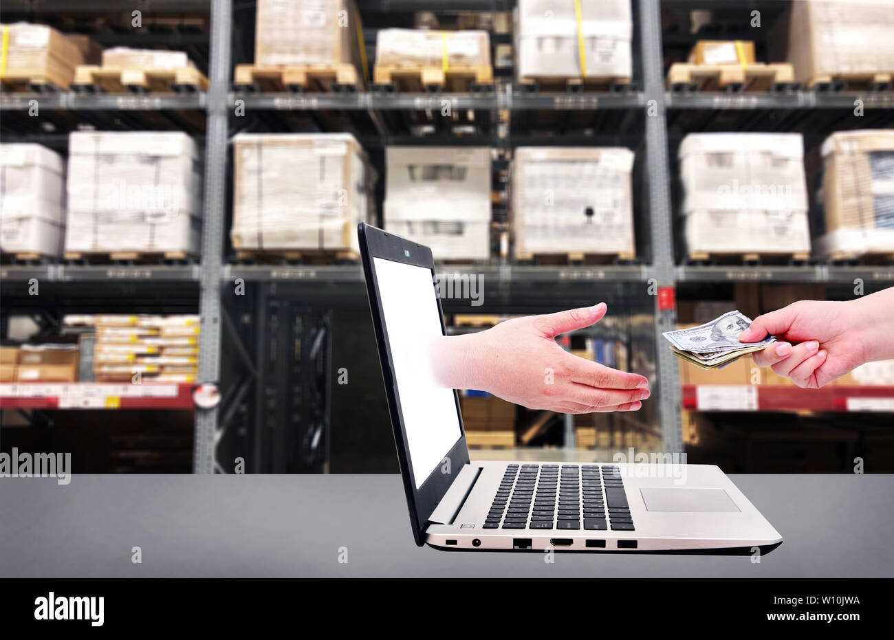 Mano dal computer portatile per ottenere il denaro e una mano azienda US dollar per pagare sul magazzino ripiani background .Online il concetto di business. Foto Stock