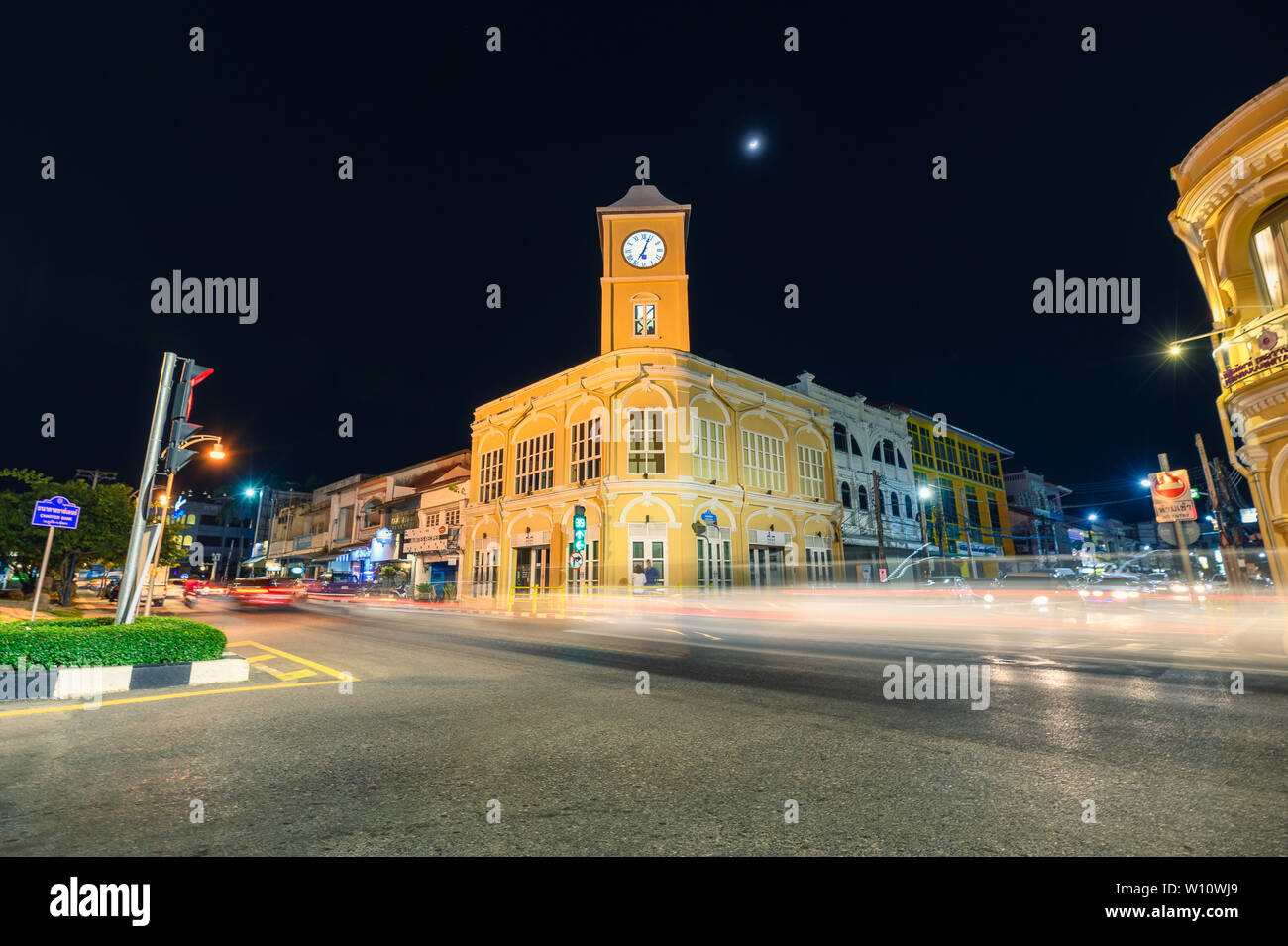 Phuket, Tailandia - 2018 Dic 12 : Punto di riferimento di clock di giallo edificio a torre con traffico su crossway di notte Foto Stock