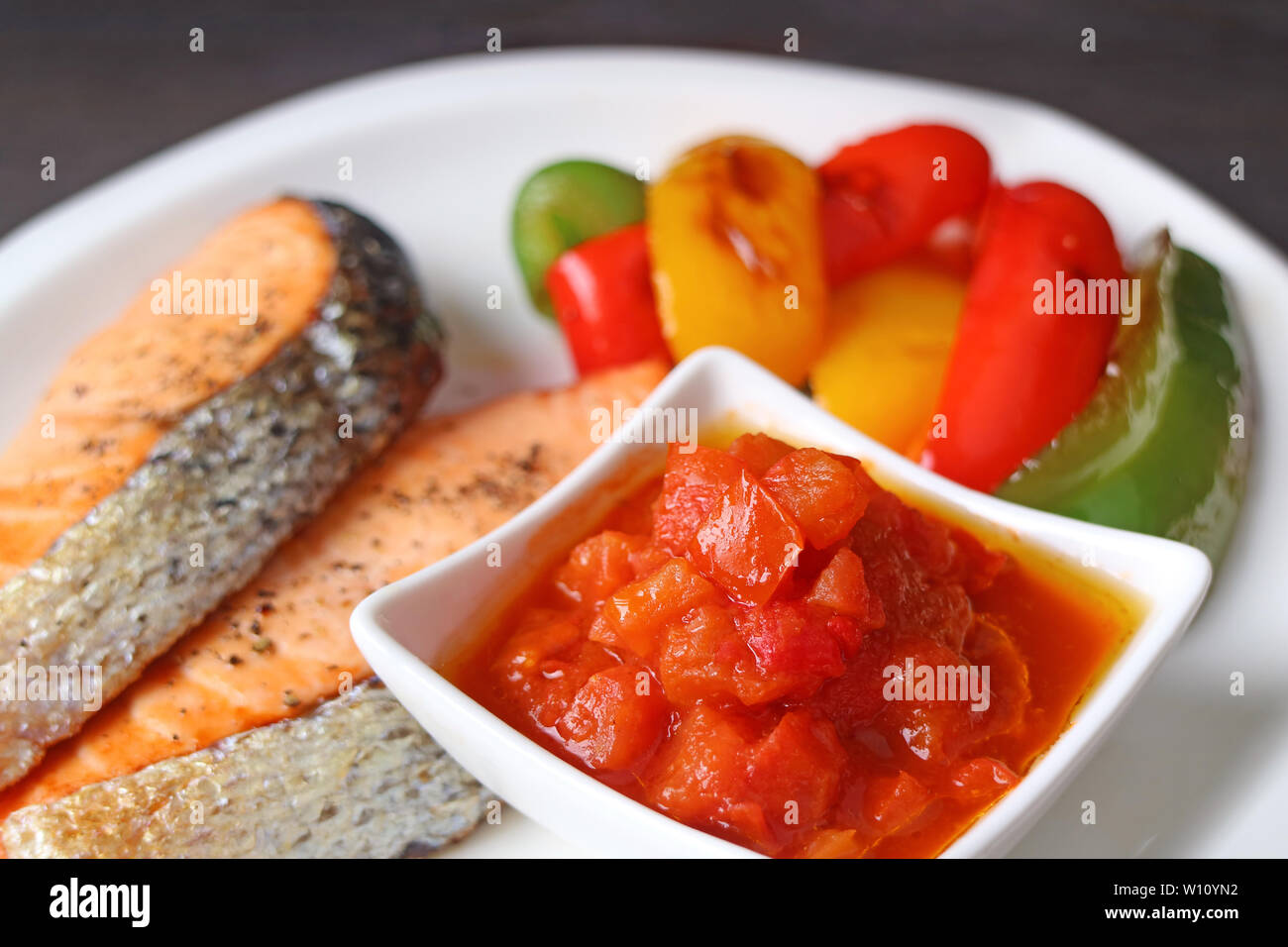 Ciotola di deliziosa salsa di pomodoro per grigliate di filetti di salmone Foto Stock