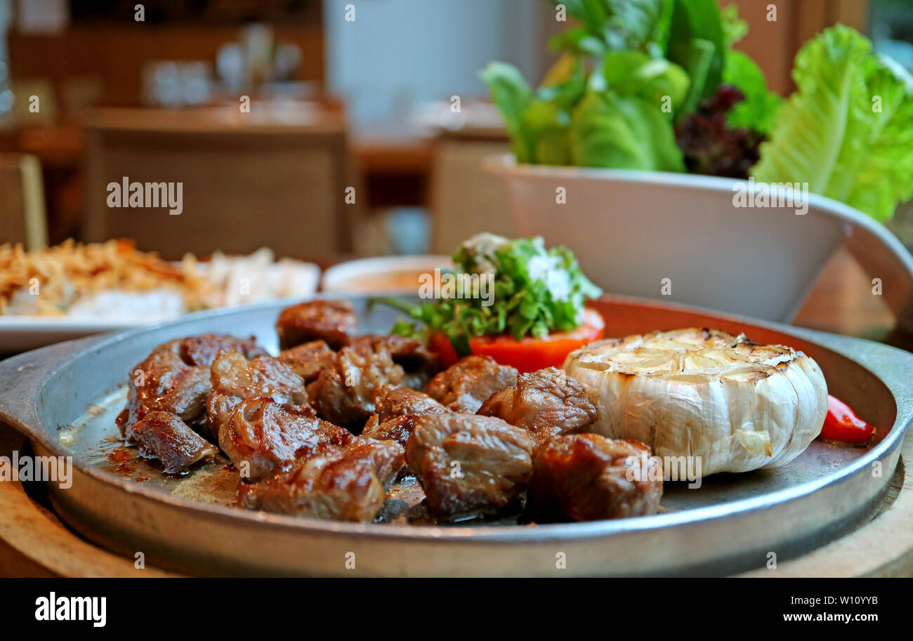 Closeup sfrigolanti bistecca di manzo con sfocata verdura fresca in background Foto Stock