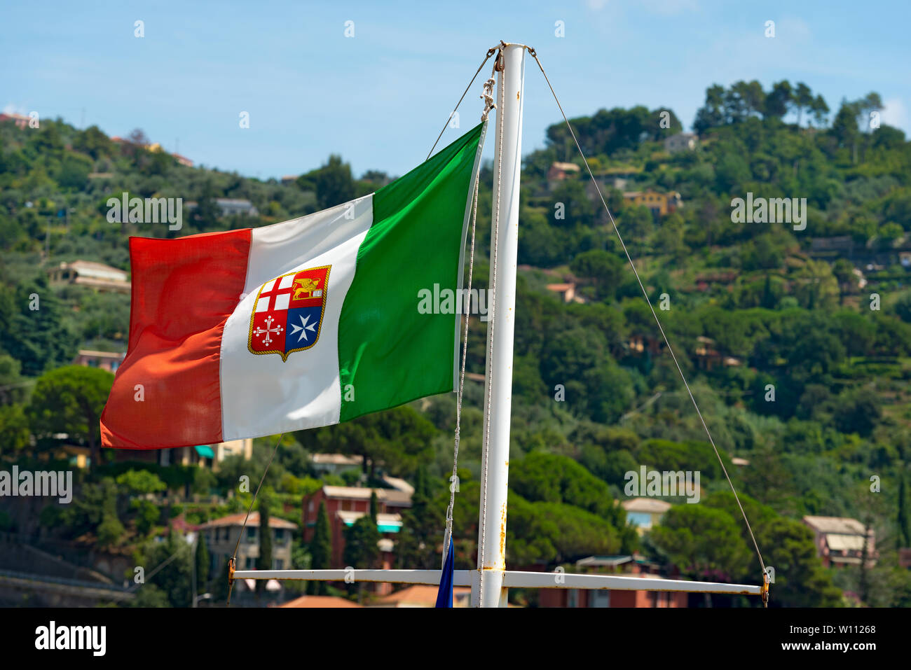 Bandiera Italiana con stemma delle quattro Repubbliche Marinare, Venezia, Genova, Pisa e Amalfi appeso su una nave il montante. Verde collina sullo sfondo Foto Stock