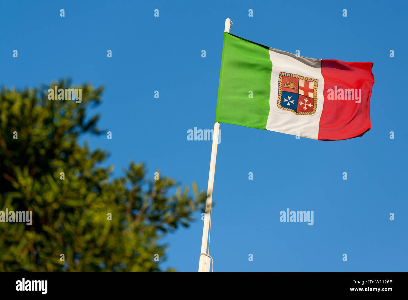 Bandiera Italiana con stemma delle quattro Repubbliche Marinare, Venezia, Genova, Pisa e Amalfi, su un cielo blu Foto Stock