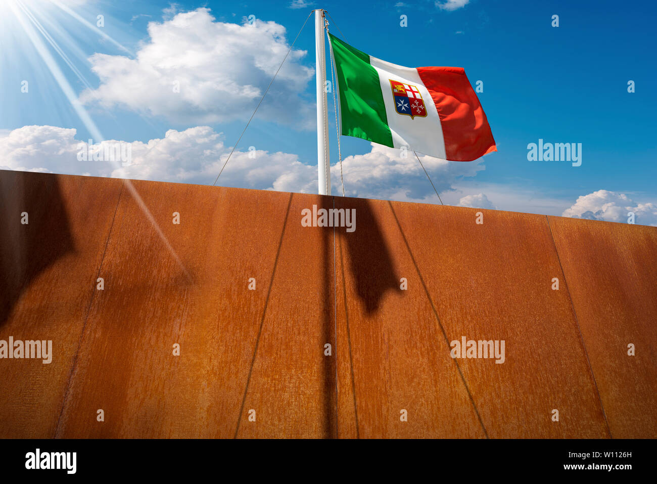 Bandiera Italiana con stemma delle quattro Repubbliche Marinare, Venezia, Genova, Pisa e Amalfi appeso su una nave sul montante di cielo blu con nuvole e raggi solari Foto Stock