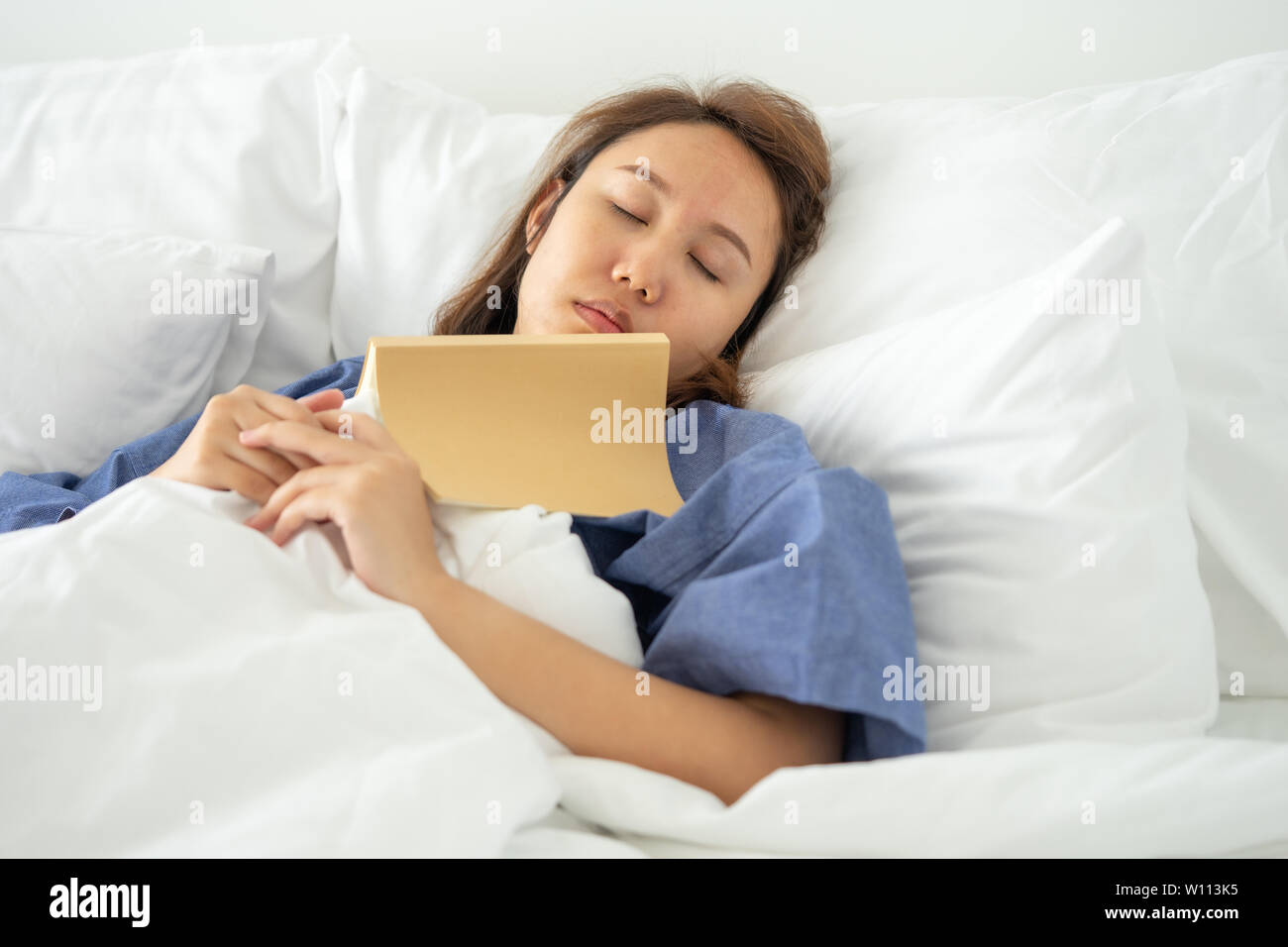 Ragazza asiatica leggere libri mentre dorme. L'uomo per la copertina del libro provoca sonnolenza sonno.Il concetto di sonno adeguato. Buon sonno Foto Stock