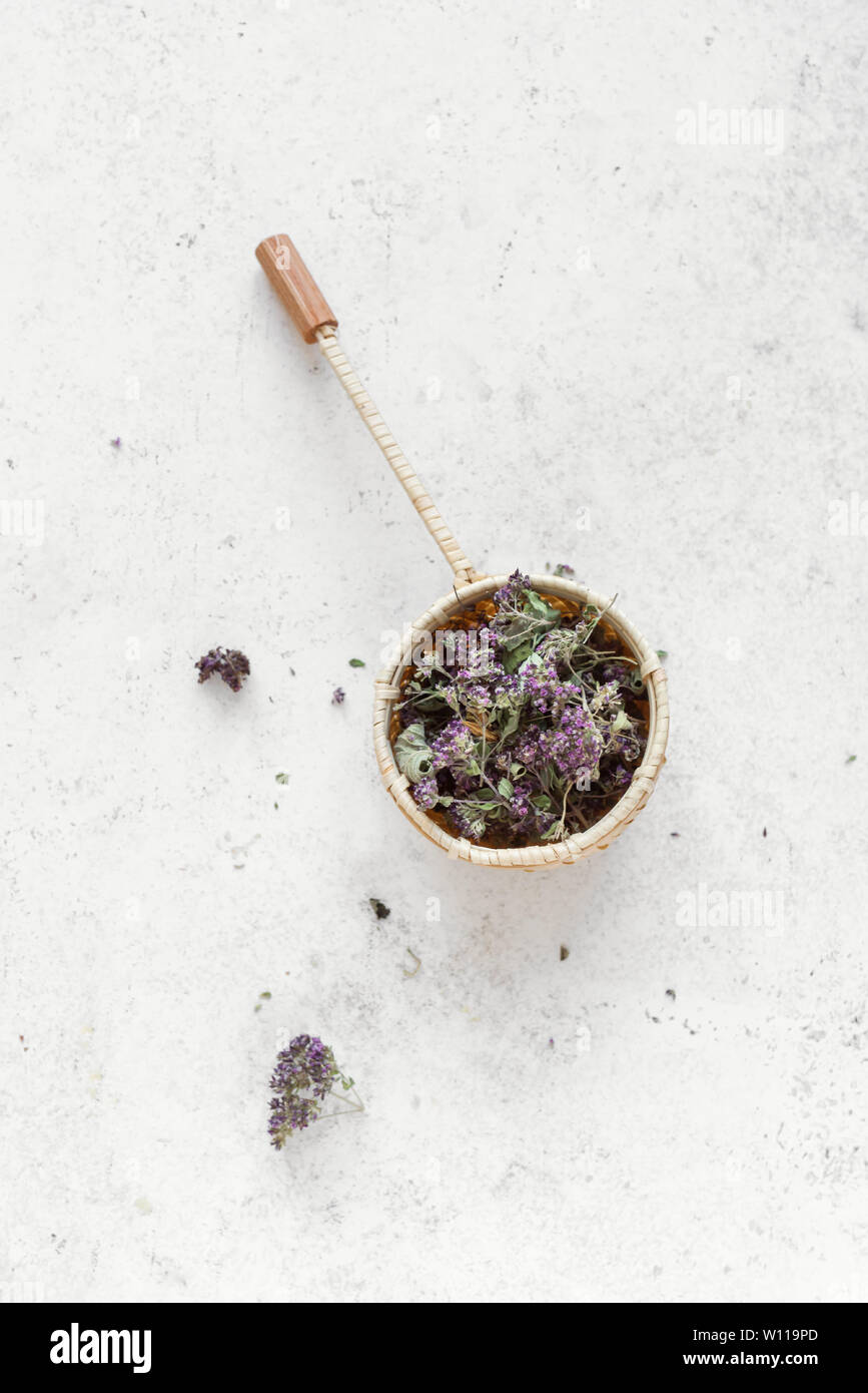 Il tè alle erbe su sfondo bianco, vista dall'alto, copia dello spazio. Stainer tè con origano essiccato e fiori di lavanda, naturale tè alle erbe composizione. Foto Stock