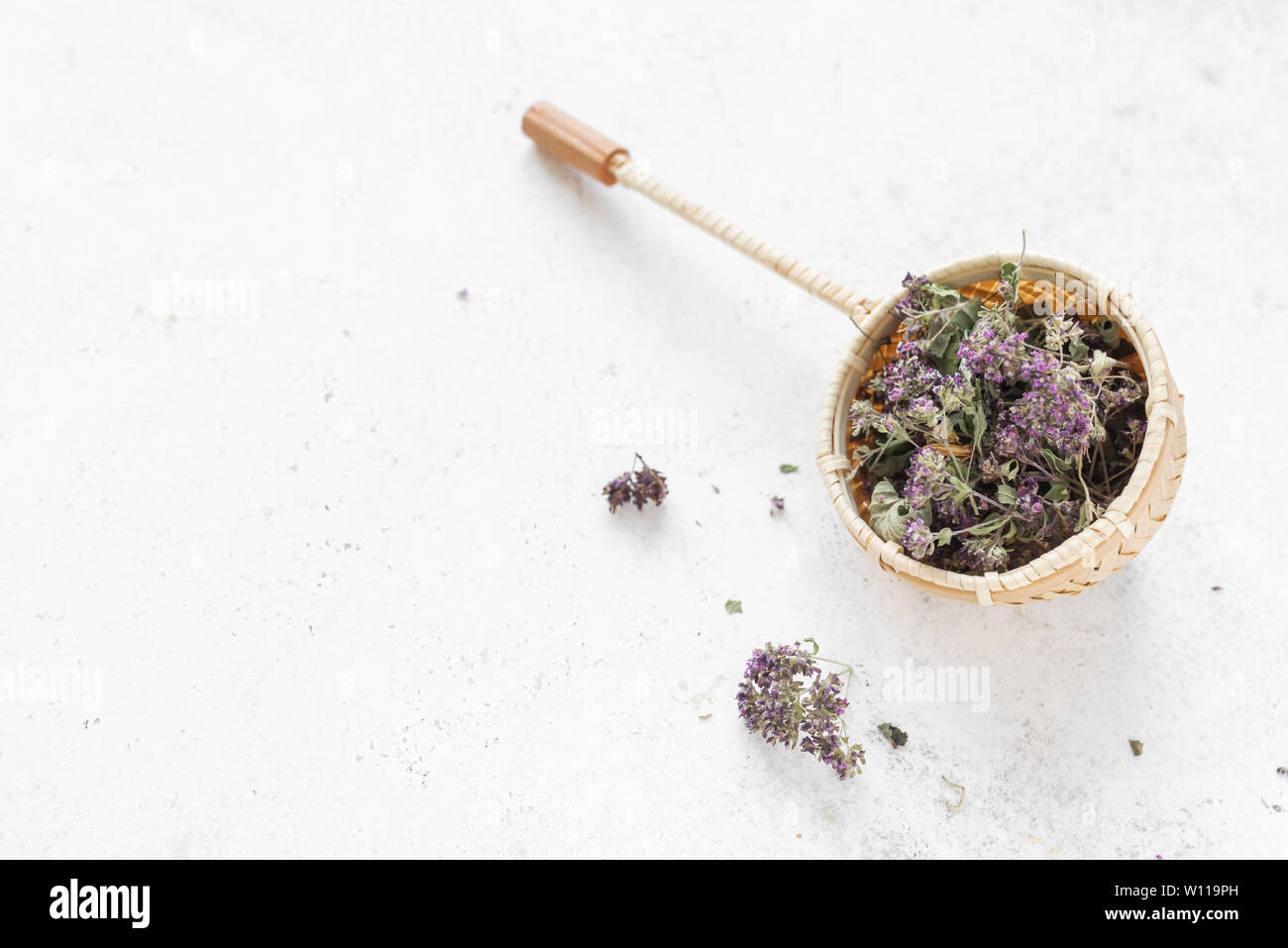 Il tè alle erbe su sfondo bianco, vista dall'alto, copia dello spazio. Stainer tè con origano essiccato e fiori di lavanda, naturale tè alle erbe composizione. Foto Stock