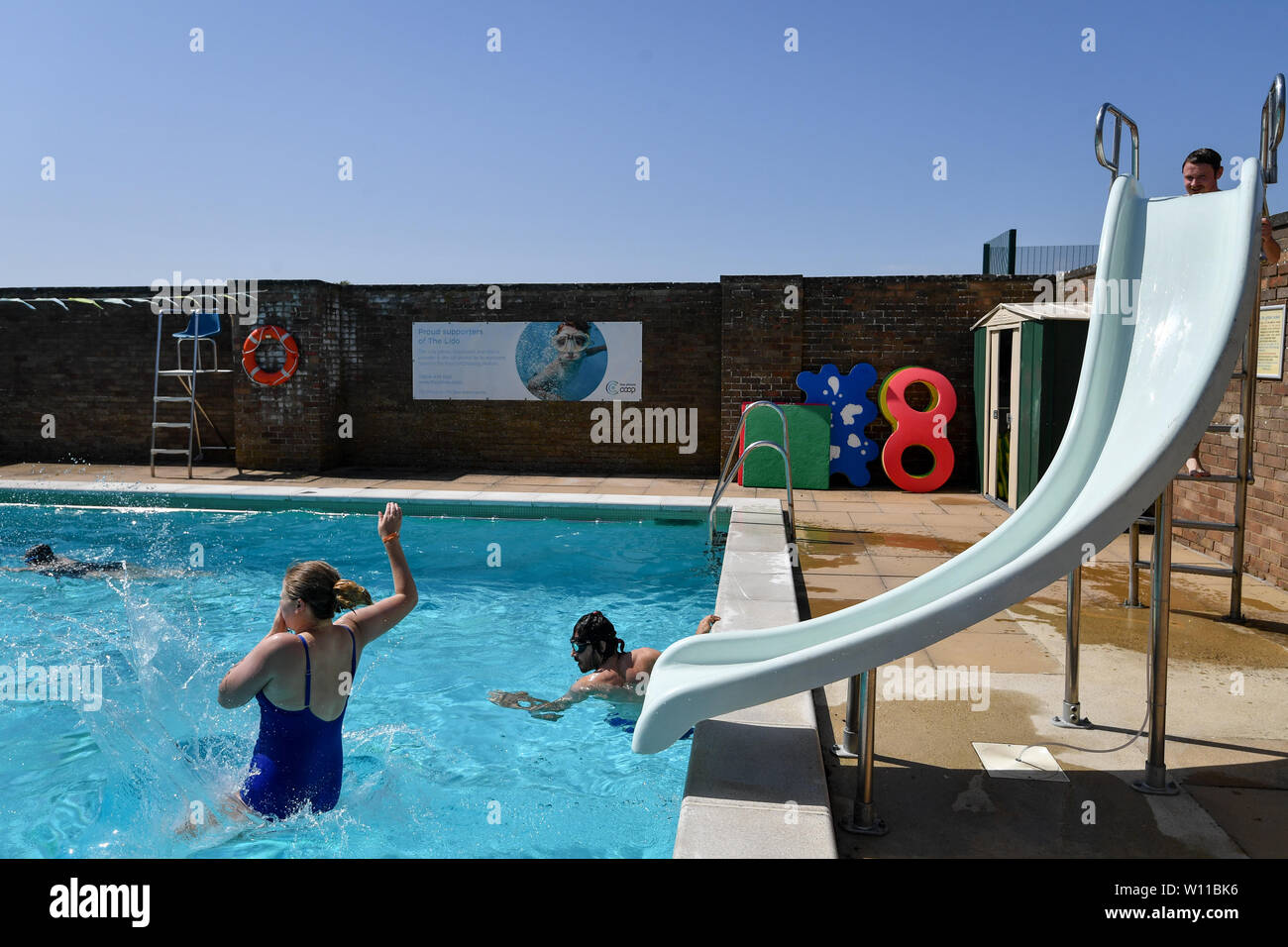 Un nuotatore utilizza la slitta al Lido in Chipping Norton in Oxfordshire, il giorno che potrebbe vedere un nuovo record per una temperatura di giugno nel Regno Unito. Foto Stock