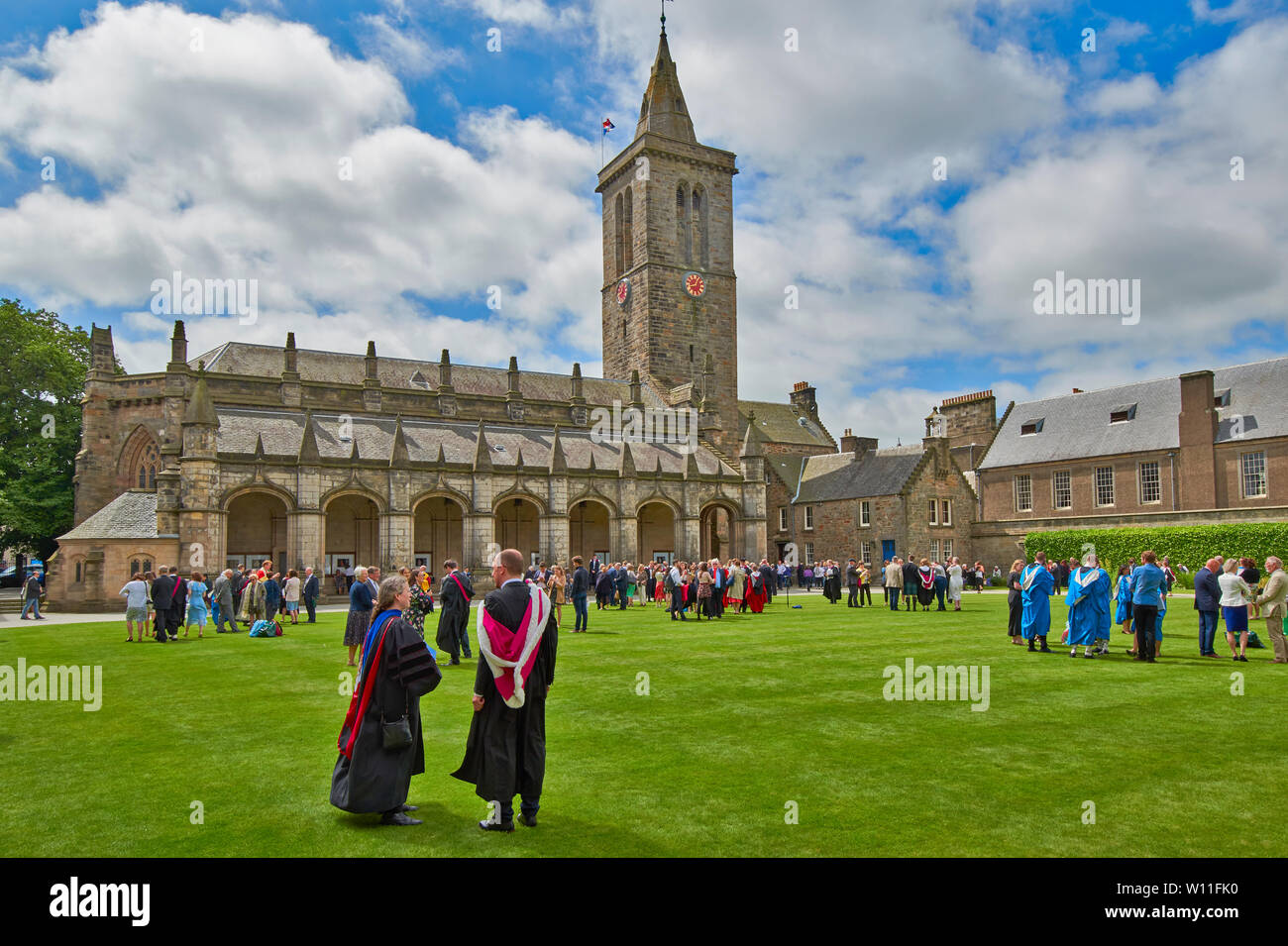 ST ANDREWS UNIVERSITY FIFE SCOZIA ST SALVATORS College e la chiesa il giorno di graduazione in estate per i laureati in abiti colorati sul prato Foto Stock