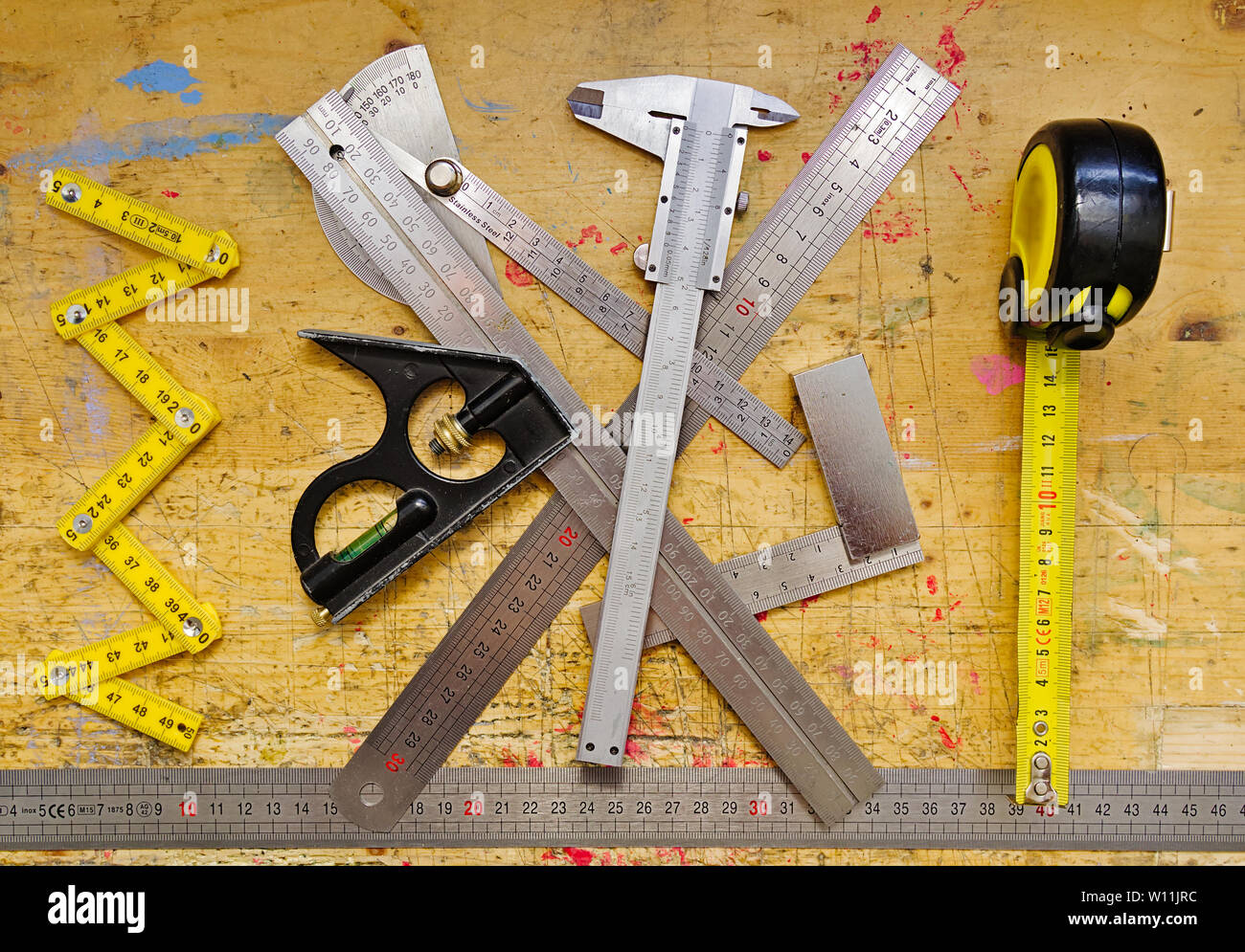 Vari strumenti di misurazione sul banco di lavoro in legno grunge spruzzi di vernice superficie. Foto Stock