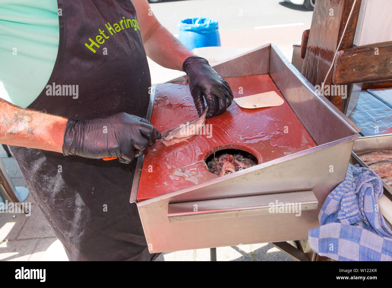 Scheveningen, Paesi Bassi - 23 Giugno 2019: pesce pulizia rivenditore nuova stagione di aringhe per mangiare presso il suo negozio in stallo Foto Stock