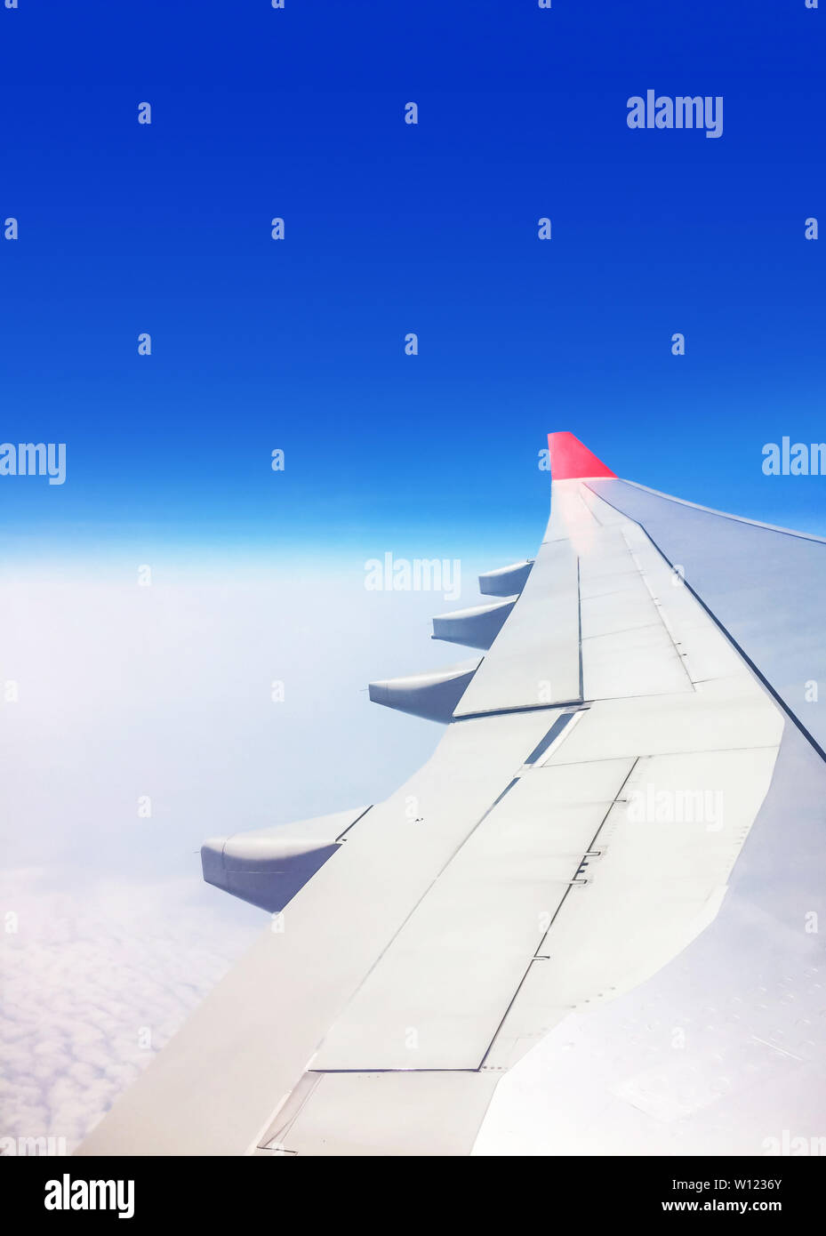 Vista di un aereo commerciale dalla finestra in cui è possibile vedere l'ala che vola sopra le nuvole ad una altezza di 35.000 piedi. Foto Stock