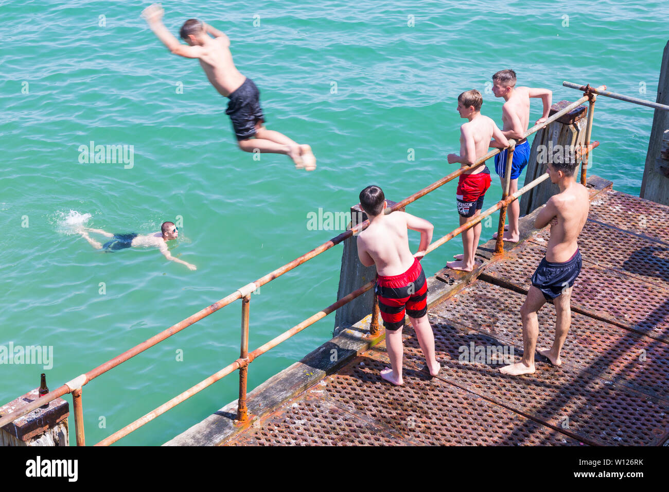 Bournemouth Dorset, Regno Unito. Il 29 giugno, 2019. Regno Unito: meteo cocente sole e caldo a Bournemouth spiagge, come testa sunseekers al mare per godersi il tempo. A metà pomeriggio e beachgoers ancora arrivare cercando di trovare uno spazio, sia in parcheggi e sulle spiagge impaccata con appena un area di ricambio di sabbia in vista sul il giorno più caldo dell'anno finora. Nonostante i segni premonitori di acque poco profonde e nessun diving o saltando i giovani ancora prendere il tuffo! Tombstoning off Bournemouth Pier. Credito: Carolyn Jenkins/Alamy Live News Foto Stock