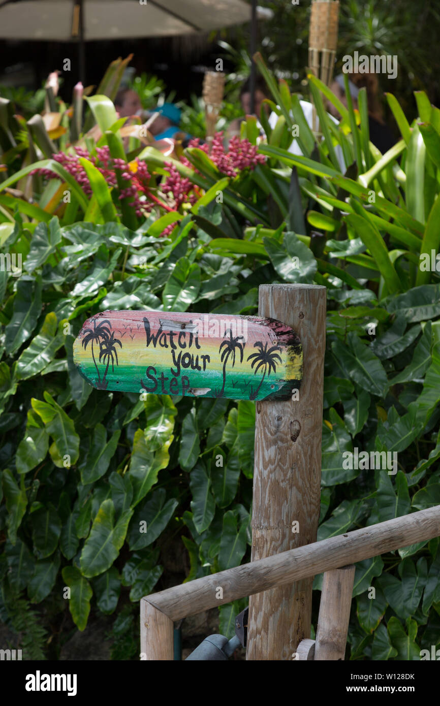 Un cartello avverte di 'guardare il vostro passo' al ristorante Guanabanas sul lungomare a Jupiter Inlet, Florida, USA. Foto Stock