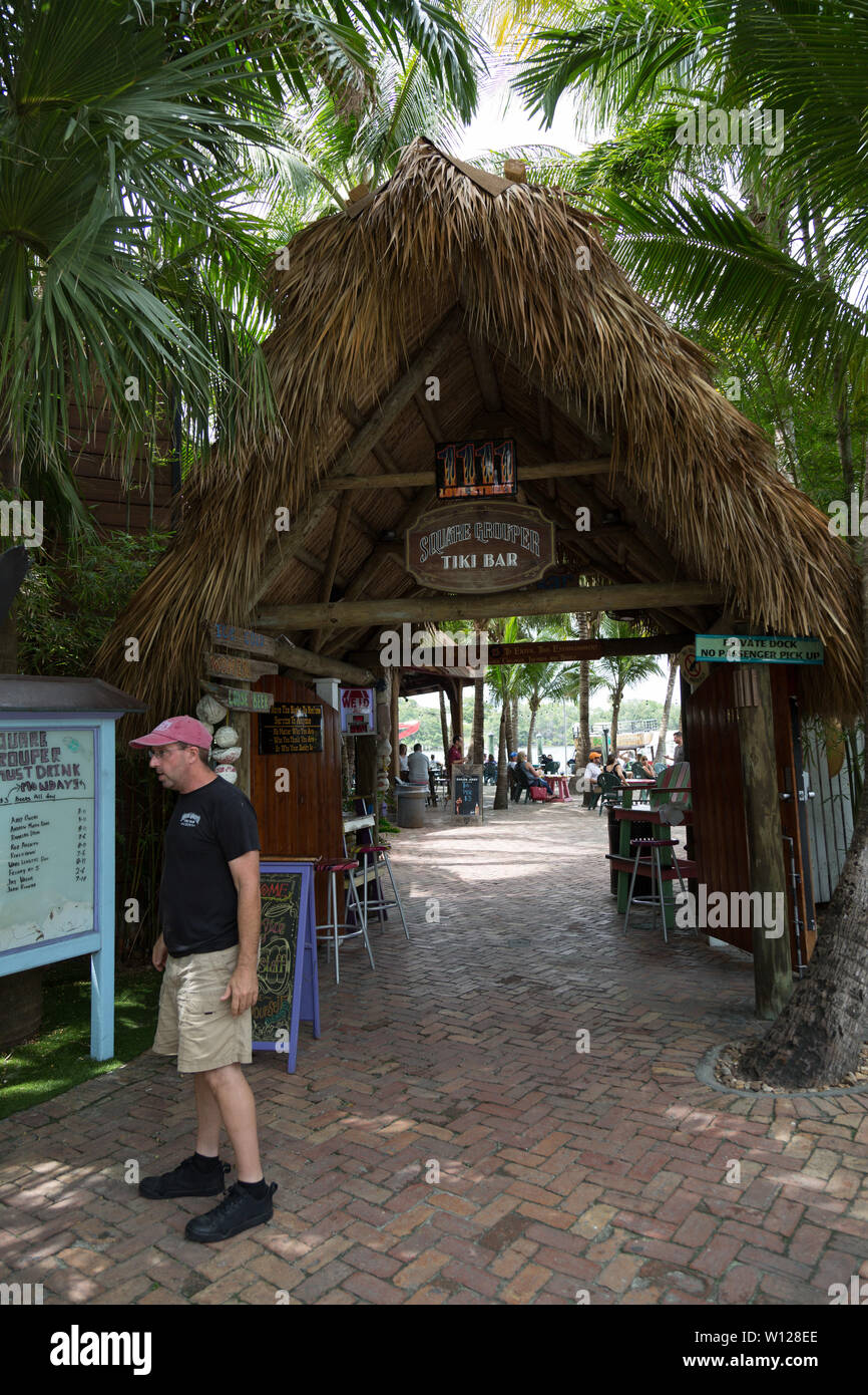 Un uomo si erge al di fuori della Piazza di cernia Tiki Bar in ingresso di Jupiter, Florida, Stati Uniti d'America. Foto Stock