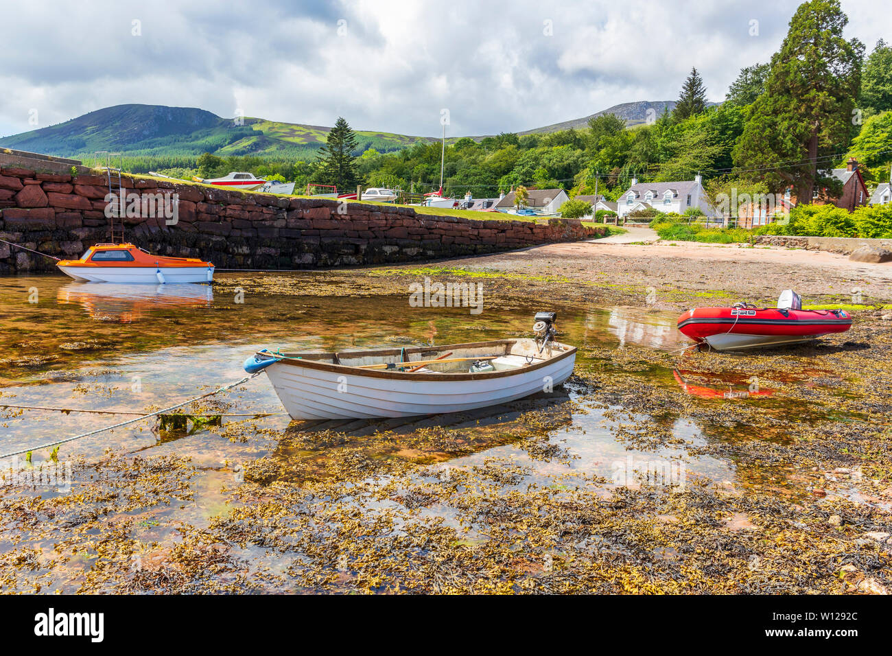 Piccolo porto a Corrie sull'isola di Arran, Firth of Clyde, Scozia con tre piccole imbarcazioni al bordo delle acque. Foto Stock