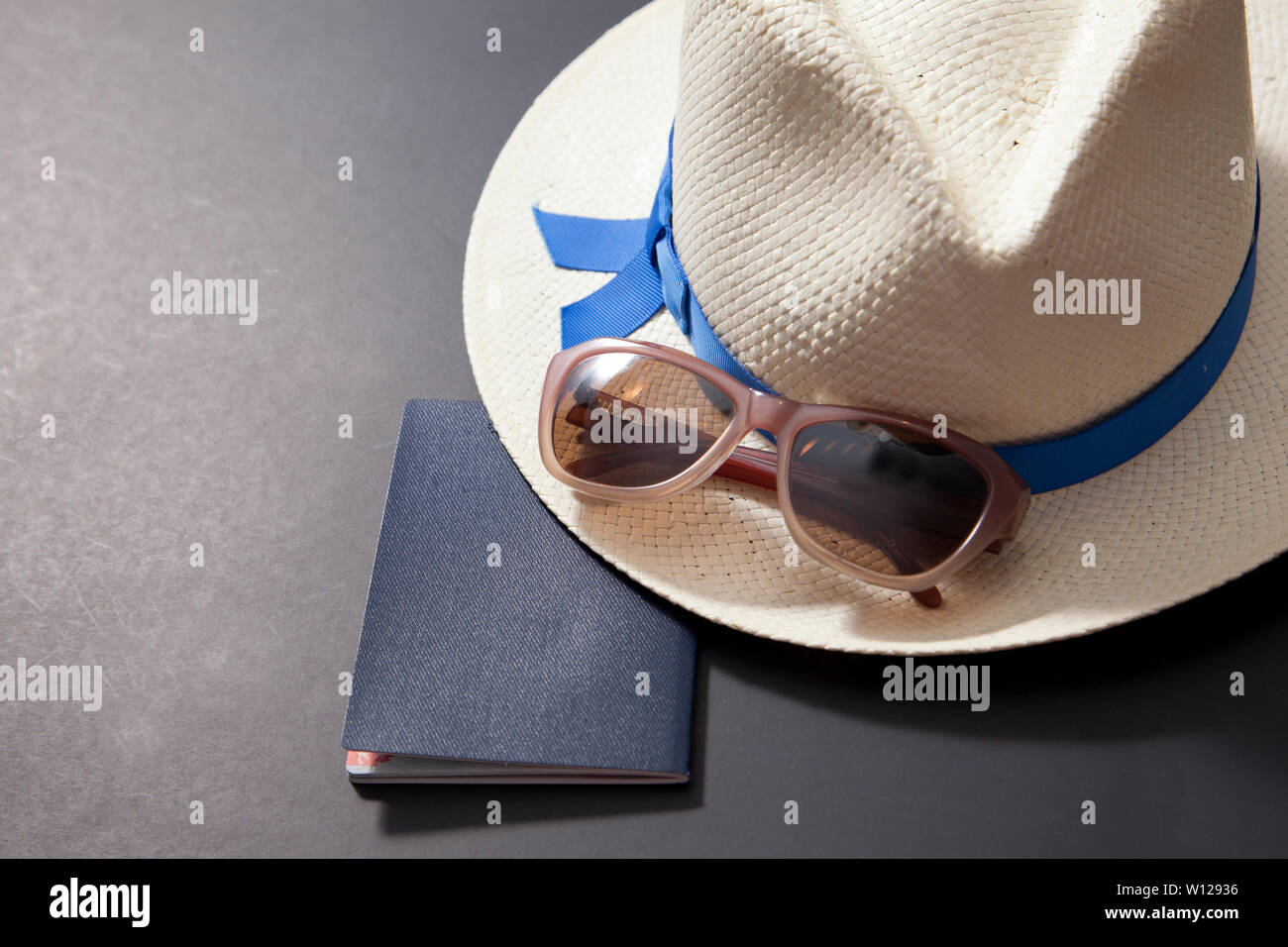 Passaporto, cappello e occhiali da sole su sfondo nero Foto Stock