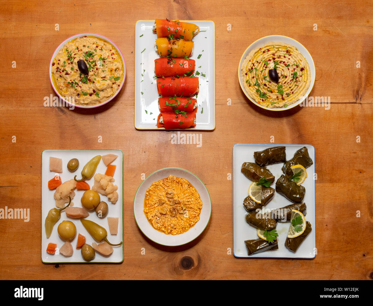 Meze turchi assortiti antipasti su un tavolo di legno - Le foglie di vite ripiene, Involtini di Peperoni, sottaceti, Hummus, Babaganoush - cucina turca Foto Stock