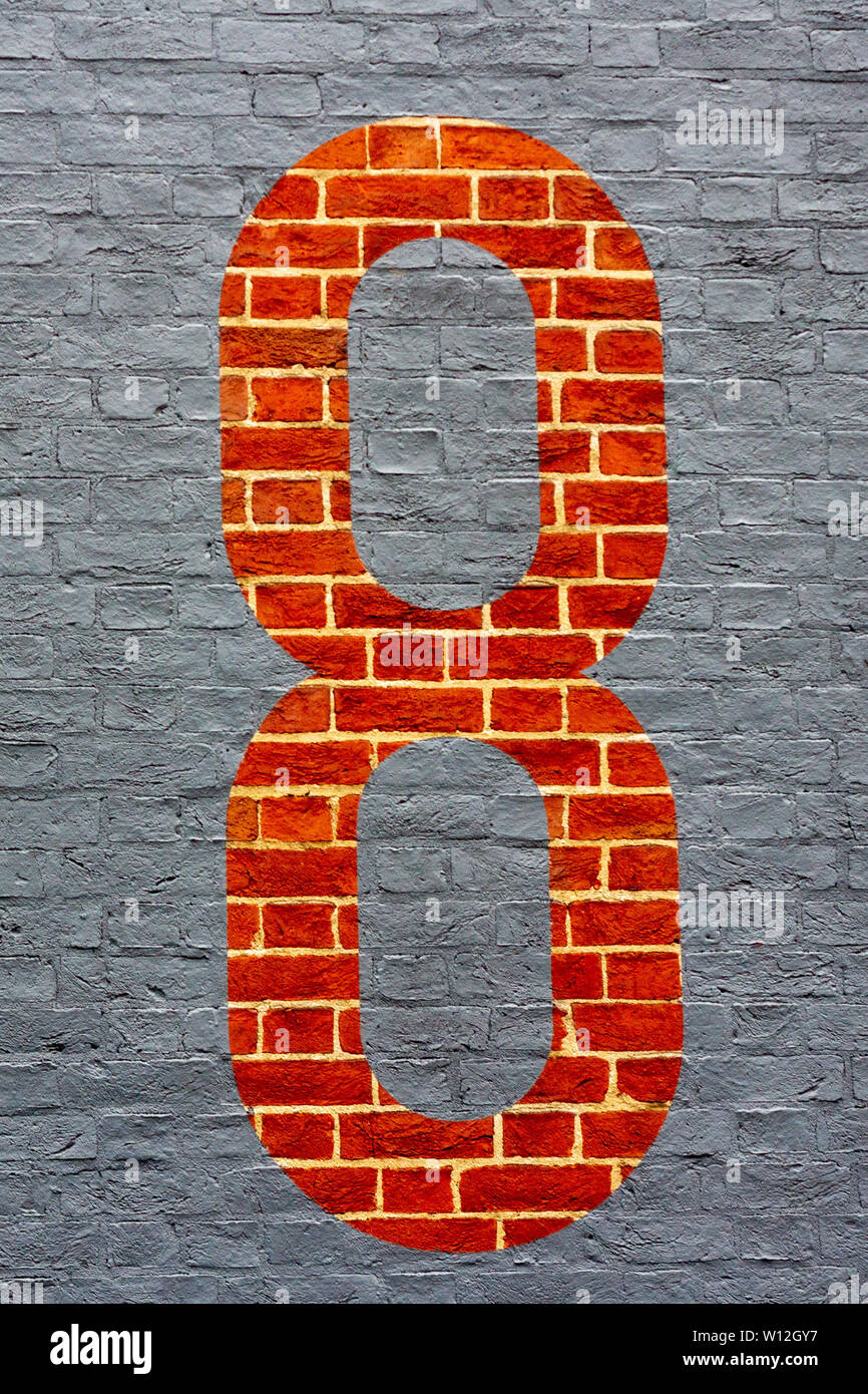 Casa numero otto con il 8 inverso dipinta come un contorno grigio su un rosso muro di mattoni Foto Stock