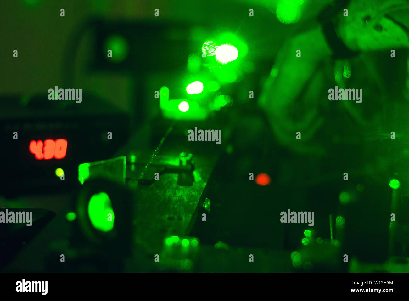 Scienziato con vetro dimostra microparticella laser, laser verde scienza ricerca Foto Stock