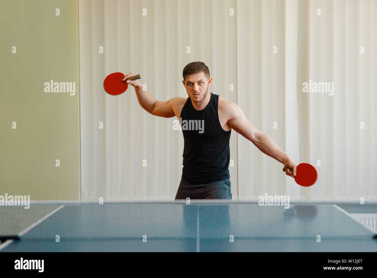 Uomo con due racchette giocando a ping pong per interni Foto Stock