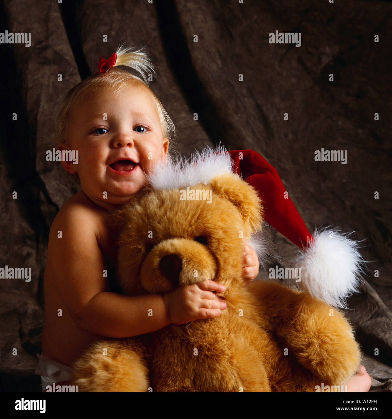 |Baby tenendo un orsacchiotto di peluche che indossa un cappello da Babbo Natale Foto Stock