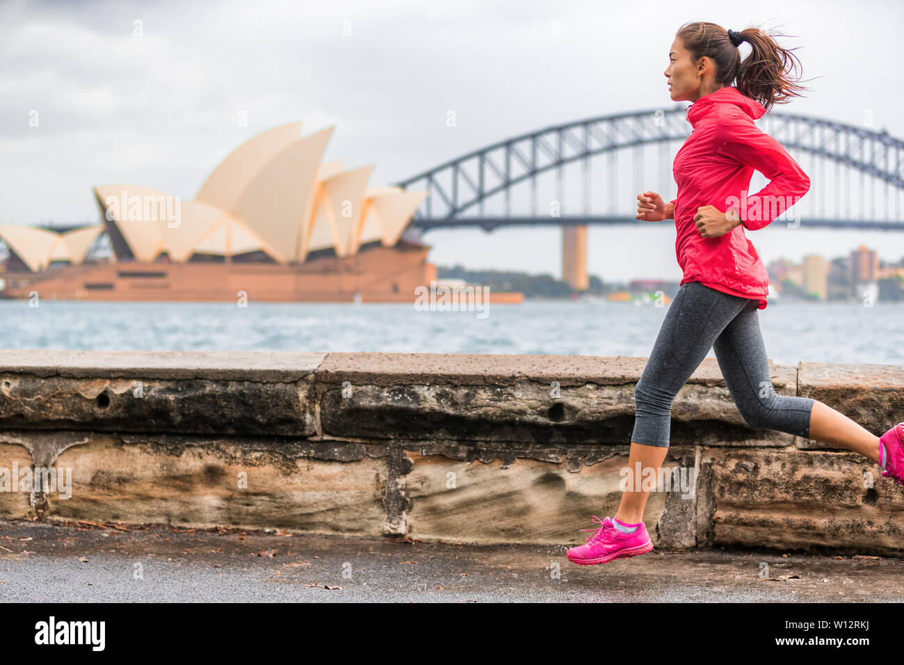 Runner montare uno stile di vita attivo donna jogging sul Porto di Sydney dall' Opera house famosa attrazione turistica di punto di riferimento. La vita della città. Foto Stock