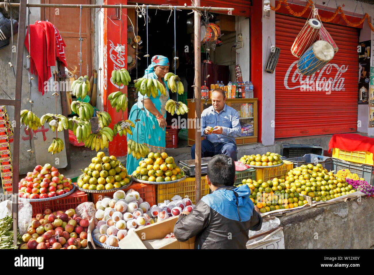 Il cliente di mangiare un succo di arancia a produrre il negozio nella piccola città mercato di Dumre Bazaar, Nepal Foto Stock