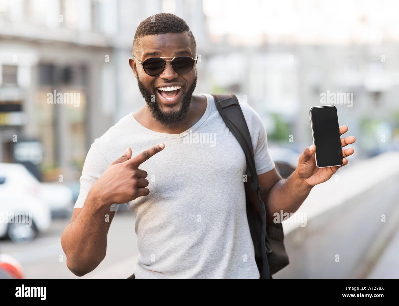Felice ragazzo africano rivolto il suo cellulare con il nero lo schermo è vuoto Foto Stock