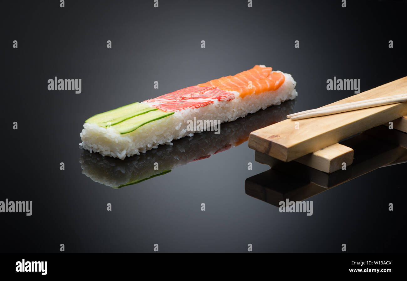 Sushi su sfondo nero con bacchette in legno per premere il modulo per rendere il sushi Foto Stock