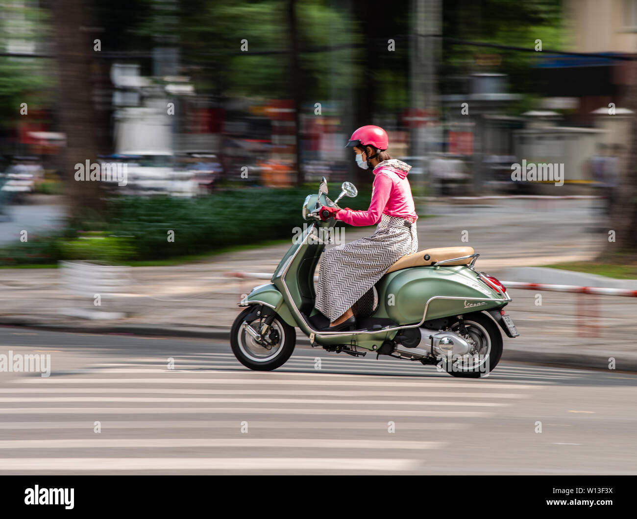 La città di Ho Chi Minh, Vietnam - Gennaio 11, 2016: giovane donna alla guida del suo elegante scooter Vespa nel centro cittadino di Ho Chi Minh City. Foto Stock