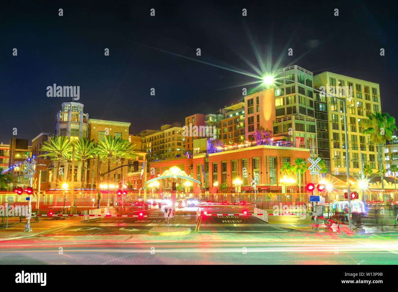 Illuminazione Pedicabs, automobili e la linea metropolitana fermata al passaggio a livello Harbor Drive tra il porto e il quartiere Gaslamp Quarter di San Diego Downtown Foto Stock