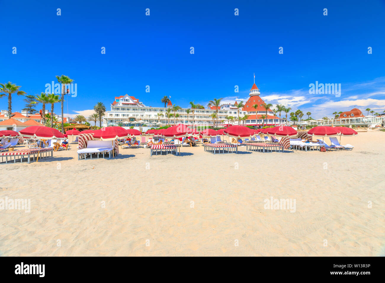 San Diego, California, Stati Uniti - 1 Agosto 2018: rosso ombrelloni e lettini in spiaggia di Coronado. Victorian Hotel Coronado, storico Foto Stock