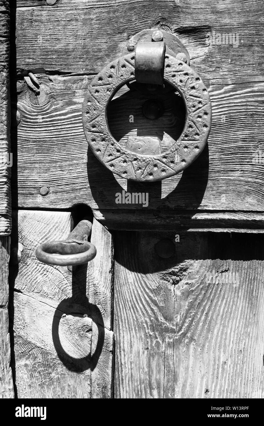 Antico metallo rustico la chiave nella serratura porta e metallo respingente da una vecchia porta di legno in Gistaín (Chistau valley, Sobrarbe, Huesca, Aragona,Spagna). B&W versione Foto Stock