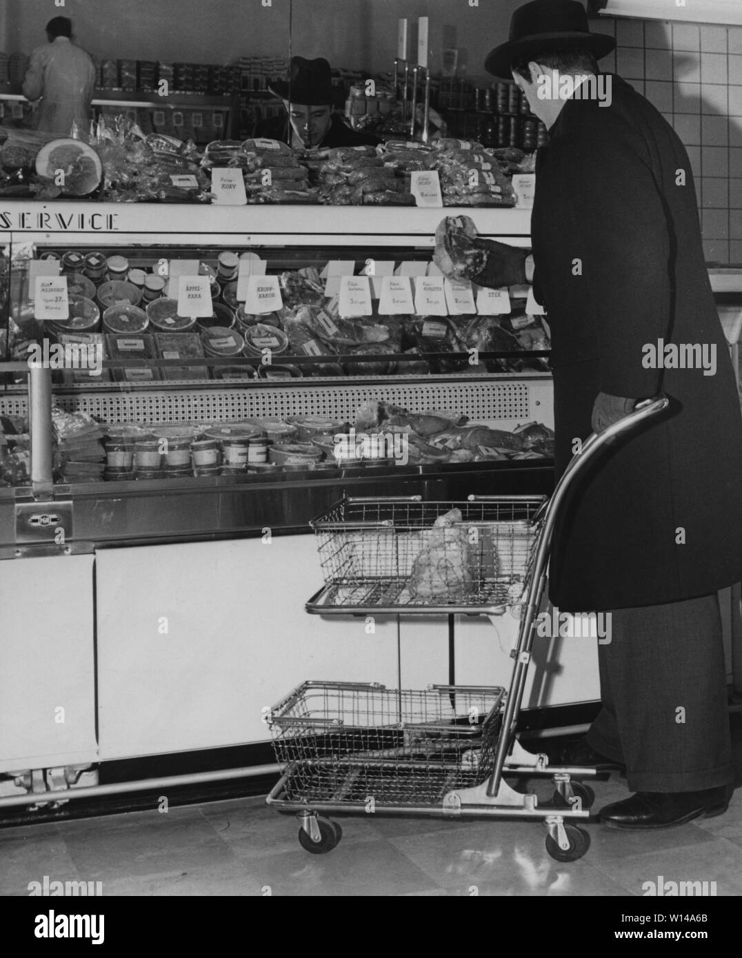 Shopping nel 1940s. Un ben vestito uomo in cappotto e hat negozi in un self service store. Sia l'idea di self service e il carrello trolley è venuto dall America e mirava a encrease vendite. Il cliente può scegliere i negozi di generi alimentari e mettere nel carrello trolley e procedere allo store checkout. La Svezia 1947 Foto Stock