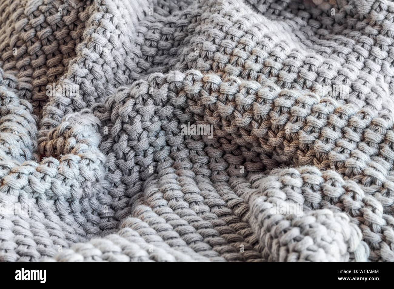 Riassunto di un morbido grigio in maglia di gettare una coperta con il fuoco selettivo in centro Foto Stock