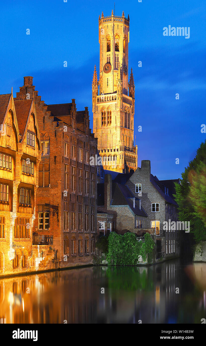 Famosa vista di Bruges turistico attrazione landmark - Rozenhoedkaai canal con la torre campanaria e le vecchie case lungo il canal grande e con albero nella notte. Belgio Foto Stock