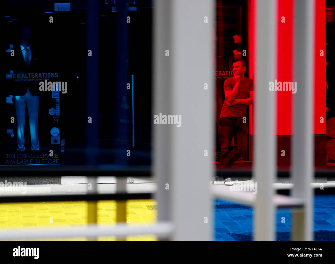 Un uomo fuma una sigaretta in Lime Street, Londra, come visto attraverso l'acciaio inox e vetro acrilico scultura 'Serie industriale ho Windows' da Marisa Ferreira, parte della scultura nella città serie. Foto Stock