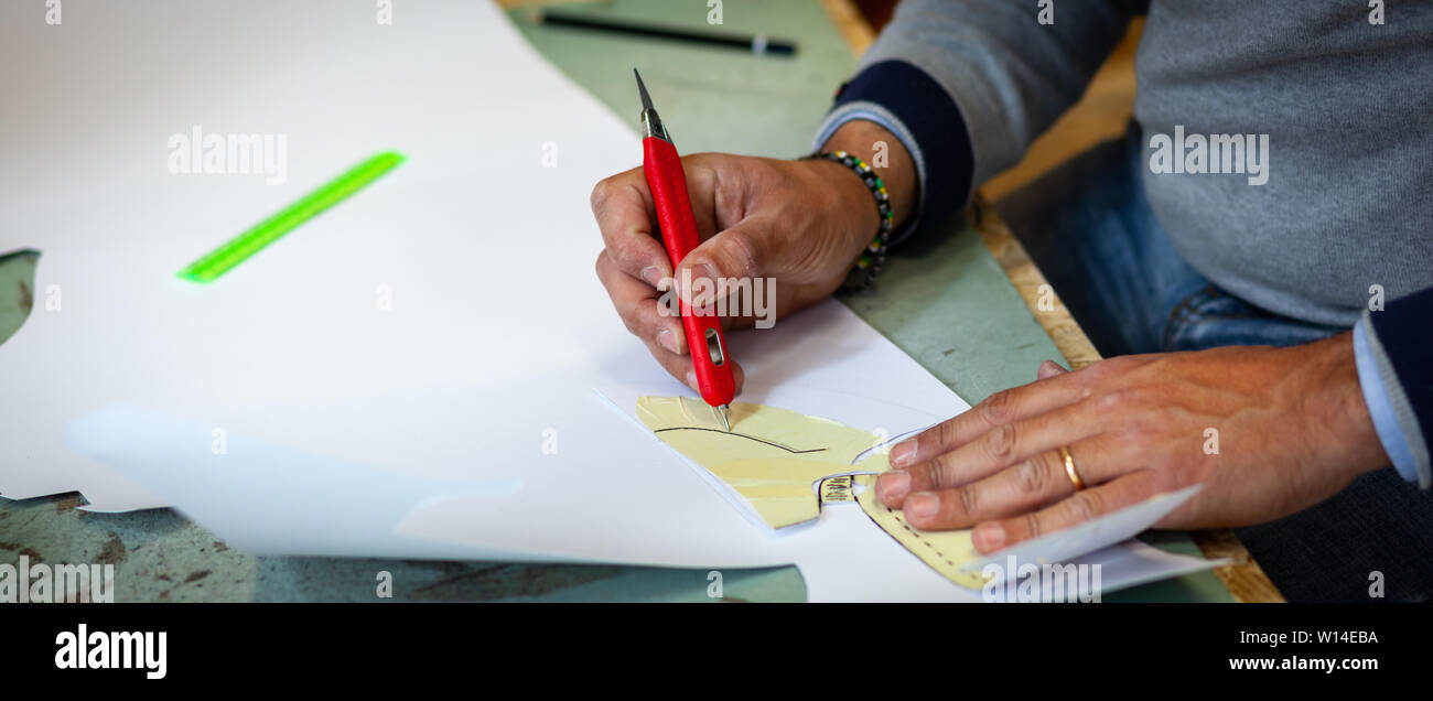 Calzolaio o scarpa designer che lavora con lcon libro modelli per taglio di pelle. Foto Stock