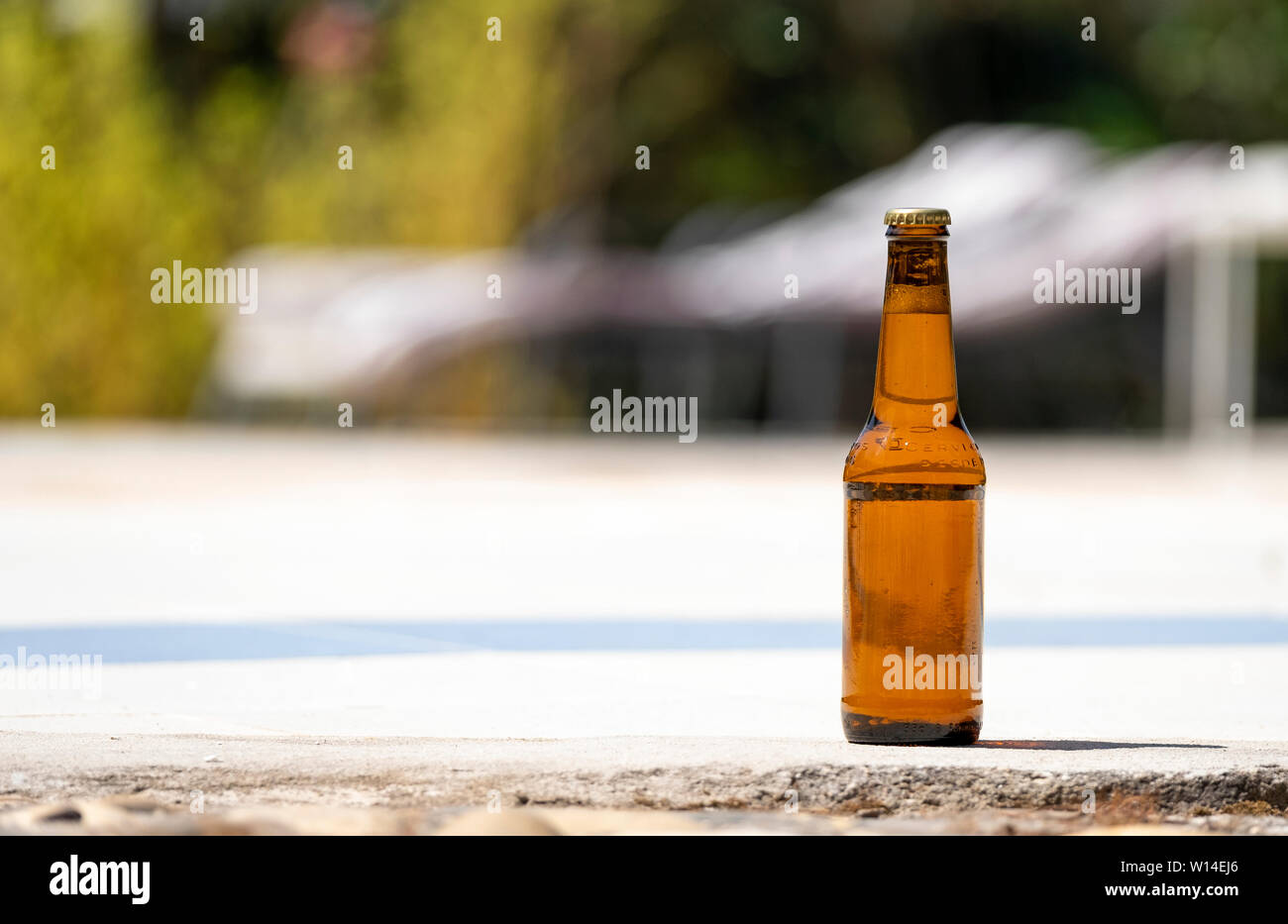 Bottiglia di birra sul bordo di una piscina Foto Stock