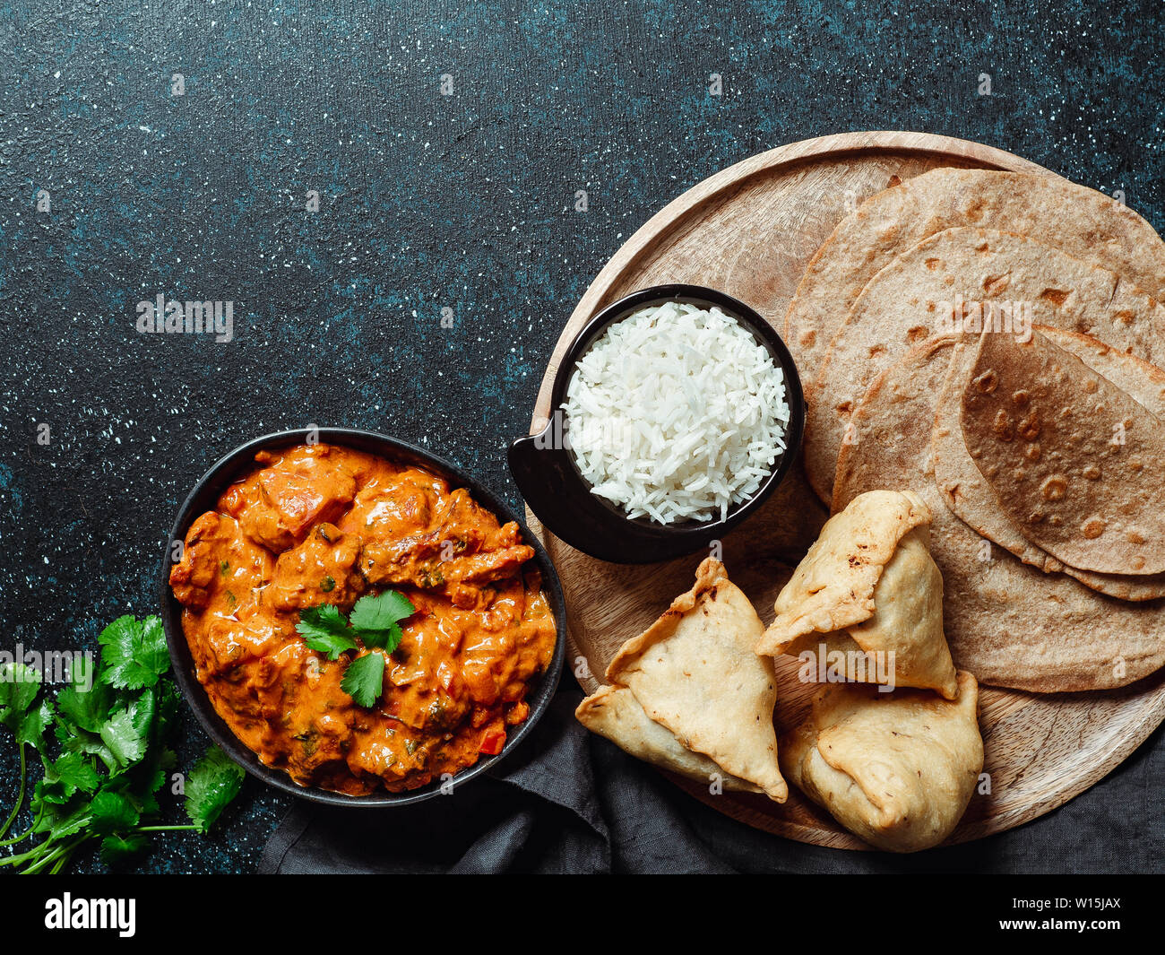 La cucina indiana piatti: tikka masala, riso, samosa, chapati,. Il cibo indiano su sfondo scuro con copia spazio. Assortimento pasto indiano vista superiore piatta o laici. Foto Stock